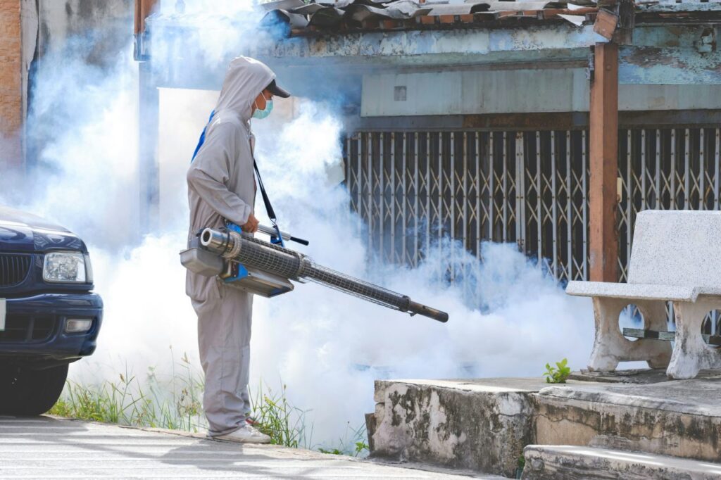 healthcare-worker-spraying-chemical-to-eliminate-mosquitoes-in-overgrown-area-at-abandoned-house.jpg