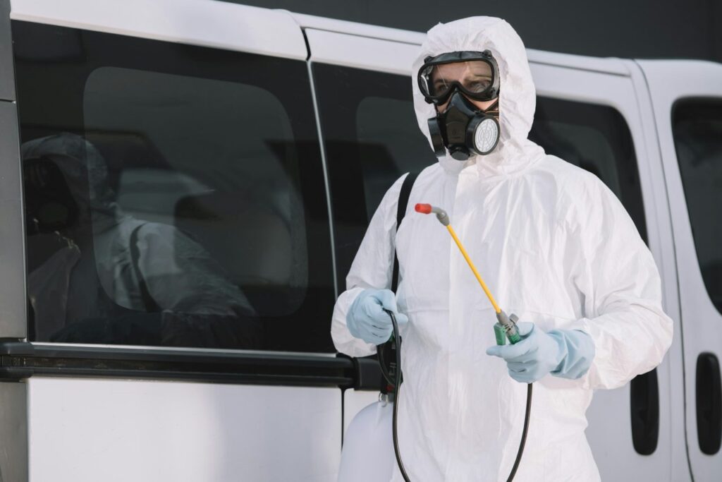 pest-control-worker-in-uniform-standing-near-car-on-street-and-holding-sprayer.jpg