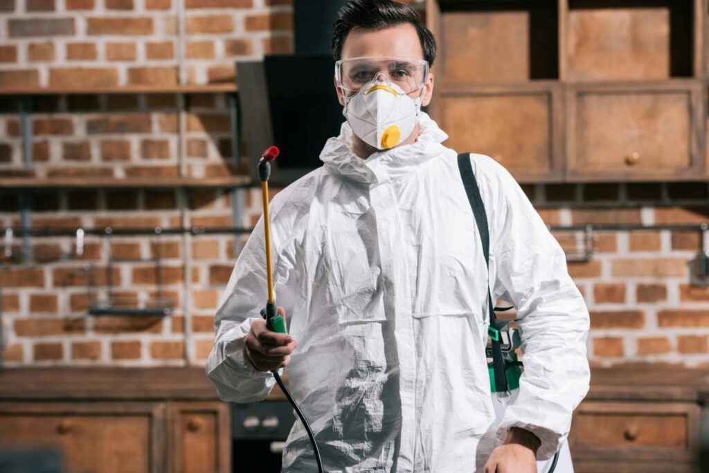 pest-control-worker-standing-with-sprayer-in-kitchen-and-looking-at-camera.jpg